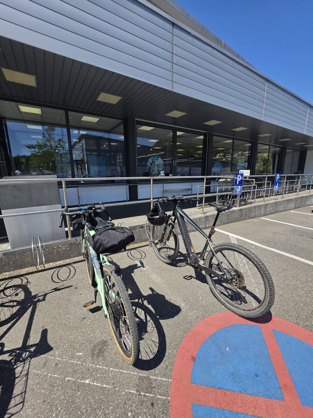 Zwei Fahrräder am Fahrradständer vor einem Aldi-Markt, Helm am Lenker