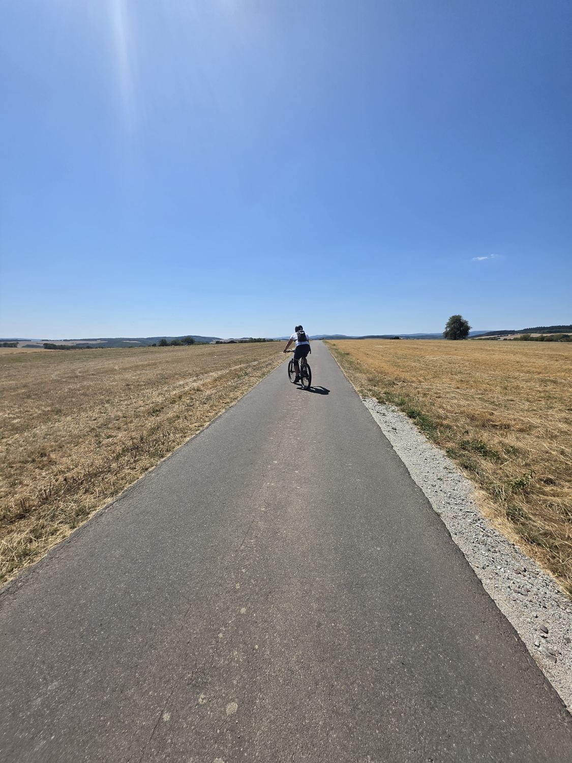 Kris fährt auf einer leeren Straße über die weite, trockene Hochfläche