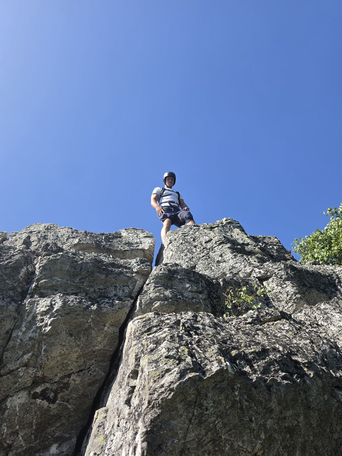 Person steht oben auf dem Quarzitfelsen Teufelsfels vor blauem Himmel